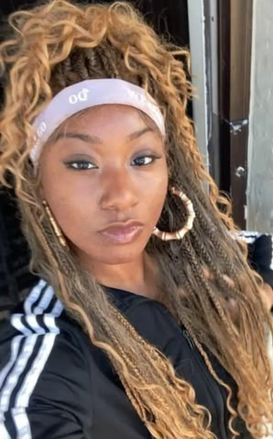 Janelle wearing honey-blonde boho braids and gold hoop earrings