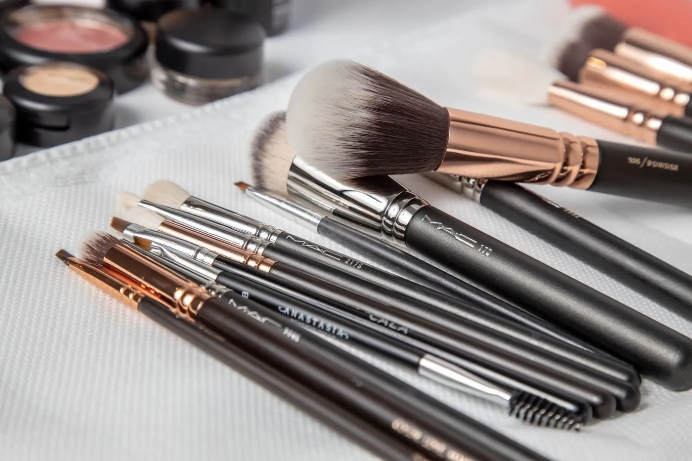 Professional makeup brushes laid out on white linen